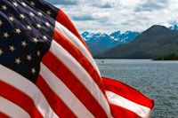 Juneau, Alaska, USA.  American flag waving in Safari Endeavour. Icy Strait. Glacier Bay National Park adn Preserve. Chichagof Island. Juneau. Southeast Alaska. Today is the ultimate day of exploration. Set your course for arguably the richest whale waters in Southeast Alaska. Keep watch for the telltale blow of the humpbacks as you scour the nutrient-rich waters in search of whales, porpoise, sea lions, and other wildlife.