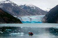Juneau, Alaska, USA. Safari Endeavour cruise passengers in an inflatable boat in front of South Sawyer Glacier calves into the Endicott Arm fjord of Tracy Arm in Fords Terror Wilderness, Southeast, Alaska. Cliff-walled fjords sliced into the mountainous mainland are on tap today as you slowly slip into an area widely acclaimed as the most beautiful in Alaska. 