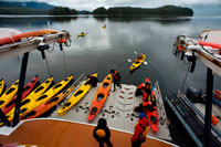 Juneau, Alaska, USA. People getting into sea kayaks on loading dock cruise ship Safari Endeavour near Reid Glacier in Glacier Bay National Park. Enjoy an evening at anchor, and mornings spent paddling your kayak in the quiet of this majestic wilderness. Here in the bay are puffins and sea lions, mountain goats and bears, moose, eagles, and scenery more spectacular than any place on earth.