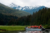 Juneau, Alaska, USA. Safari Endeavour cruise passengers in an inflatable boat in Scenery Cove, Thomas Bay, Petersburg, Southeast Alaska. Thomas Bay is located in southeast Alaska. It lies northeast of Petersburg, Alaska and the Baird Glacier drains into the bay. Thomas Bay is also known as "The Bay of Death" due to a massive landslide in 1750. It also has gained the name of "Devil's Country" when in 1900 several people claimed to have seen devil creatures in the area. Thomas Bay is known for being rich in gold and quartz. The wildlife has moose, brown bears, black bears, squirrels, wolves, rabbits, and other common Alaskan creatures. 