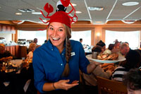 Juneau, Alaska, USA. Restaurant of Safari Endeavour cruise at Fords Terror, Endicott Arm, Tongass National Forest, Alaska, USA. The waitress teaches the dish of the day: crab. The 49th State, the largest in the U.S., is perfect for cruisers, with numerous opportunities to appreciate its vast natural beauty. 