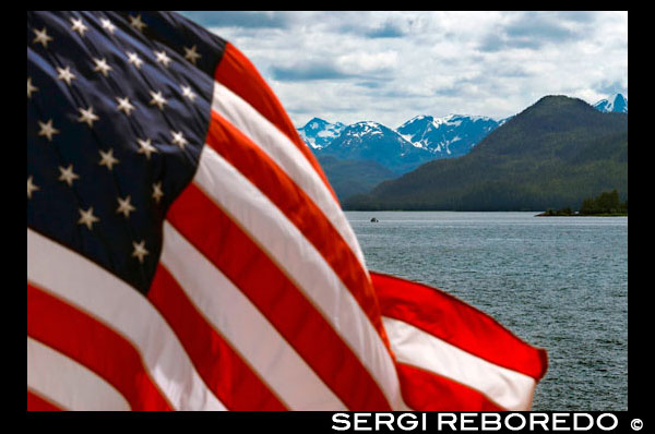 American flag waving in Safari Endeavour. Icy Strait. Glacier Bay National Park adn Preserve. Chichagof Island. Juneau. Southeast Alaska. Today is the ultimate day of exploration. Set your course for arguably the richest whale waters in Southeast Alaska. Keep watch for the telltale blow of the humpbacks as you scour the nutrient-rich waters in search of whales, porpoise, sea lions, and other wildlife. Join the Captain on the bridge or go on deck with your Expedition Leader. Late afternoon, drop the skiffs and kayaks for closer inspection of the remote coastline with eyes set on shore for possible bear sightings. This evening, take in the solitude while relaxing in the upper deck hot tub or enjoy a nightcap with your fellow yachtmates in the saloon.