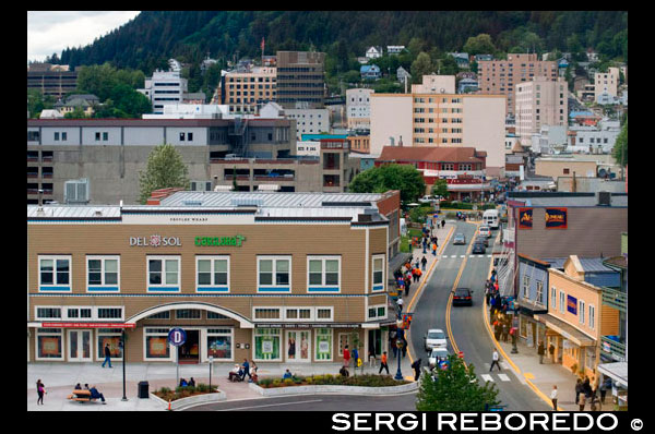 Juneau downtown, from the Mount Roberts Tramway. Alaska. USA. Diferents shops and stores in Juneau. South Franklin Street. The City and Borough of Juneau is the capital city of Alaska. It is a unified municipality located on the Gastineau Channel in the Alaskan panhandle, and is the second largest city in the United States by area. Juneau has been the capital of Alaska since 1906, when the government of what was then the District of Alaska was moved from Sitka as dictated by the U.S. Congress in 1900. The municipality unified on July 1, 1970, when the city of Juneau merged with the city of Douglas and the surrounding Greater Juneau Borough to form the current home rule municipality. The area of Juneau is larger than that of Rhode Island and Delaware individually and is almost as large as the two states combined. Downtown Juneau  is nestled at the base of Mount Juneau and across the channel from Douglas Island. As of the 2010 census, the City and Borough had a population of 31,275. In July 2013, the population estimate from the United States Census Bureau was 32,660, making it the second most populous city in Alaska after Anchorage.(Fairbanks is however the second-largest metropolitan area in the state, with more than 97,000 residents.) Between the months of May and September, Juneau's daily population can increase by roughly 6,000 people from visiting cruise ships.