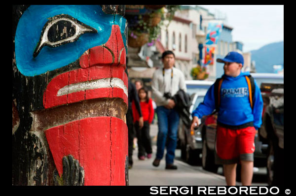 Totem and tourists walking in the streets of Juneau. Alaska, USA. The City and Borough of Juneau is the capital city of Alaska. It is a unified municipality located on the Gastineau Channel in the Alaskan panhandle, and is the second largest city in the United States by area. Juneau has been the capital of Alaska since 1906, when the government of what was then the District of Alaska was moved from Sitka as dictated by the U.S. Congress in 1900. The municipality unified on July 1, 1970, when the city of Juneau merged with the city of Douglas and the surrounding Greater Juneau Borough to form the current home rule municipality. The area of Juneau is larger than that of Rhode Island and Delaware individually and is almost as large as the two states combined. Downtown Juneau  is nestled at the base of Mount Juneau and across the channel from Douglas Island. As of the 2010 census, the City and Borough had a population of 31,275. In July 2013, the population estimate from the United States Census Bureau was 32,660, making it the second most populous city in Alaska after Anchorage.(Fairbanks is however the second-largest metropolitan area in the state, with more than 97,000 residents.) Between the months of May and September, Juneau's daily population can increase by roughly 6,000 people from visiting cruise ships. 