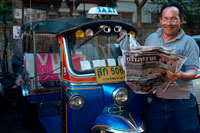 Bangkok. Tuk tuk driver reading the newpaper. Tuk-tuks or 'sam lor' (three-wheeled) used to be everyone's favourite way of getting around Bangkok before the BTS, MRT and colourful taxis took over. Originating from an old-fashioned rickshaw during the second World War, a tuk-tuk is essentially a rickshaw with a small engine fitted in. Tuk-tuks have become one of Bangkok's most recognisable transportation features, and are still popular among tourists and visitors. Riding a tuk-tuk is more of an experience rather than a practical way to get around. So, if it's your first time in The Big Mango, there's no harm in giving it a go.