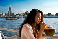 Bangkok. Romantic nice girl in a boat near Wat Arun Temple and Chao Praya River. Drinking a coconout. Chao Phraya Tourist Boat. The BTS Skytrain joins hands with Bangkok's biggest public water transportation provider, the Chao Phraya Express Boat Co.,Ltd. (established 38 years ago) to introduce a new water transportation service "The Chao Phraya Tourist Boat". This service provides tourists with the opportunity to see Bangkok from a whole new perspective, within one day, tourist can easily travel on high quantity boats from pier to pier without worrying about purchasing boat tickets or getting lost. 