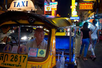 Bangkok. Tuk tuk taxi in the street. View down Thanon Yaowarat road at night in central Chinatown district of Bangkok Thailand. Yaowarat and Phahurat is Bangkok's multicultural district, located west of Silom and southeast of Rattanakosin. Yaowarat Road is the home of Bangkok's sizable Chinese community, while those of Indian ethnicity have congregated around Phahurat Road. By day, Yaowarat doesn't look that much different from any other part of Bangkok, though the neighbourhood feels like a big street market and there are some hidden gems waiting to be explored. But at night, the neon signs blazing with Chinese characters are turned on and crowds from the restaurants spill out onto the streets, turning the area into a miniature Hong Kong (minus the skyscrapers). 
