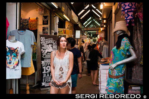 Woman buying clothes in stores at Chatuchak Weekend Market or Jatujak Market; is one of the world's largest weekend markets covers area of 70 rai (27 Acres) altogether divided into 27 Sections, contains more than 15,000 booths selling goods from every part of Thailand. Chatuchak Weekend Market,is very popular shopping centre to Thais and has become a popular place to tourists and foreigners who stay in Bangkok, has over 200,000 visitors each day(SAT-SUN) 30% is foreign. There are almost everything can be found here at a bargaining local price (not a tourist price), and most vendors actually come from local factories, like antique wood carving, clay handicrafts, local souvenirs from every parts of Thailand, Buddhist amulets, wooden funitures, hand made decorated flowers, plant, ceramic wares, dools, Thai Bejarong, Chinese wares, graden decorated plants, stones, trendy fashions, silk, hill-tribe outfits, fluffy dogs and more miscellaneous, etc.