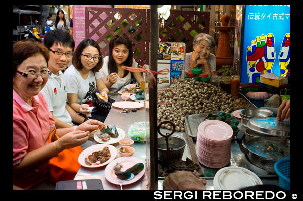Restaurants a la carretera Thanon Yaowarat a la nit al cèntric barri de Chinatown de Bangkok, Tailàndia. Yaowarat i Phahurat és multicultural barri de Bangkok, situada a l'oest de Silom i sud-est de Rattanakosin. Yaowarat Road és la llar de la comunitat xinesa gran de Bangkok, mentre que els d'ètnia índia s'han congregat al voltant Phahurat Road. Durant el dia, Yaowarat no es veu molt diferent de qualsevol altra part de Bangkok, encara que el barri se sent com un gran mercat del carrer i hi ha algunes joies ocultes esperant a ser explorat. Però a la nit, els rètols de neó resplendents amb caràcters xinesos estan encesos i les multituds dels restaurants es deixen caure pels carrers, convertint la zona en una miniatura de Hong Kong (menys els gratacels). Phahurat és un lloc excel·lent per a la compra de teles, accessoris i objectes religiosos. Una visita a la zona no està completa sense comptar amb alguns dels seus menjars sorprenents que es venen per una absoluta ganga - com niu d'ocell o alguns curris indis. El barri xinès de Bangkok és una atracció turística popular i un refugi d'aliments per gourmands de nova generació que es reuneixen aquí després del capvespre per explorar la vibrant cuina a peu de carrer. A l'hora del dia, no és menys concorregut, com hordes de compradors descendeixen sobre aquesta franja d'1 km i adjacent Charoenkrung camí per obtenir valor d'un dia de primera necessitat, l'or del comerç, o pagar una visita a un dels temples xinesos. Ple de llocs de mercat, restaurants de carrer i una densa concentració de botigues d'or, el barri xinès és una experiència que no et perdis. L'energia que emana de les seves interminables files de fusta cases-botiga és pla contagiosa - que el mantindrà amb ganes de tornar per més. Organitzeu la vostra visita durant els grans festivals, com l'Any Nou Xinès, i veurà Bangkok Chinatown en el seu millor moment.