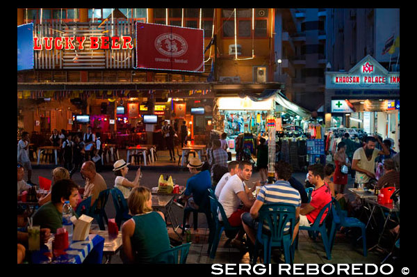 Bares, restaurantes y vida nocturna en la calle Khao San. Bangkok. Puesto de comida. Bangkok. Khaosan Road o Khao San Road es una calle corta en el centro de Bangkok, Tailandia. Es en la zona de Banglamphu (distrito de Phra Nakhon) cerca de 1 kilómetro (0,62 millas) al norte del Gran Palacio y el Wat Phra Kaew. "Khaosan" se traduce como "arroz blanco", un recordatorio de que en otros tiempos la calle era un importante mercado de arroz Bangkok. En los últimos 20 años, sin embargo, Khaosan Road se ha convertido en un famoso "gueto mochilero". Ofrece alojamiento económico, que van desde hoteles de estilo "colchón en una caja" a un precio razonable hoteles de 3 estrellas. En un ensayo sobre la cultura mochilero de Khaosan Road, Susan Orlean lo llamó "el lugar de desaparecer". También es una base del viaje: entrenadores salen todos los días para los principales destinos turísticos de Tailandia, de Chiang Mai, en el norte de Ko Pha Ngan, en el sur, y hay muchas agencias de viajes relativamente baratos que puede organizar los visados ??y transporte a los vecinos países de Camboya, Laos, Malasia y Vietnam. Tiendas Khaosan venden artesanías, pinturas, ropa, frutas locales, CD piratas, DVDs, una amplia gama de documentos de identidad falsos, libros de segunda mano, además de muchos artículos mochileros útiles. Durante la última tarde, las calles se convierten en bares y se reproduce la música, los vendedores ambulantes de alimentos venden insectos a la parrilla, aperitivos exóticos para los turistas, y también hay gente flagelación espectáculos de ping pong. Hay varios pubs y bares donde los mochileros se reúnen para discutir sus viajes. La zona es conocida internacionalmente como un centro de baile, la fiesta, y justo antes del Año Nuevo tailandés tradicional (el festival de Songkran) 13-15 de abril de salpicaduras de agua que por lo general se convierte en una enorme guerra de agua. Un escritor tailandés ha descrito Khaosan como "... un camino corto que tiene el sueño más largo del mundo". [2] Un templo budista bajo patrocinio real, la centenaria Wat Chana Songkram, está justo enfrente de Khaosan Road hacia el oeste , mientras que el área al noroeste contiene una comunidad islámica y varias mezquitas pequeñas.