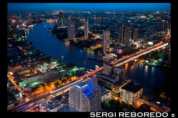 Panoramic viws and landcape of Bangkok from Sirocco rooftop. Thailand. Asia, Bangkok, capital, Centara Grand, Chao Praya River, City, cocktails, dome, Drinks, dusk, Lebua St. Sirocco rooftop bar at Lebua hotel, Bangkok, Thailand. The sense of 'having arrived' at one of Bangkok's most iconic restaurants begins with the ascent to the 63rd floor and the walk down the artistically lit staircase, with the city below and the soothing strains of the jazz band resonating through the warm breeze. Sirocco is the world's largest all open-air restaurant and "Sky Bar", located on the 64th floor of the State Tower in Bangkok, Thailand, which is the second tallest building in Thailand. The 150-capacity restaurant opened its doors in the winter of 2003. Its main feature is a spectacular 270° panorama of the Chao Phraya river and Bangkok city. Sirocco was designed by global architectural and interior design firm, dwp | Design Worldwide Partnership with the design team led by Executive Director, Scott Whittaker. Sirocco serves Mediterranean food and has a live band every evening. 