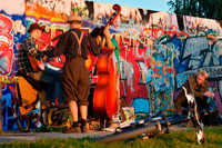Musicians. Buskers by the Wall in Mauerpark Berlin in evening light Germany. Mauerpark is a public linear park in Berlin's Prenzlauer Berg district. The name translates to "Wall Park", referring to its status as a former part of the Berlin Wall and its Death Strip. The park is located at the border of Prenzlauer Berg and Gesundbrunnen district of former West Berlin. In the 19th and 20th centuries, the Mauerpark area served as the location of the Old Nordbahnhof ("Northern Railway Station"), the southern terminus of the Prussian Northern Railway opened in 1877-78, which connected Berlin with the city of Stralsund and the Baltic Sea.
