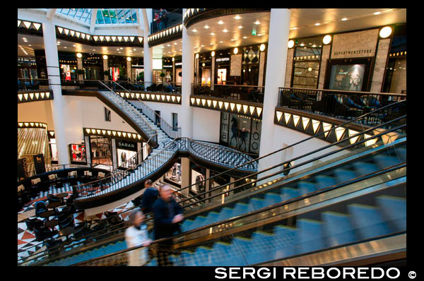 Quartier 205, luxury shopping mall in Berlin. Friedrichstrasse is one of the most legendary streets in the whole city, combining the tradition of the ‘Golden Twenties’ with the architecture of Berlin beyond 1989. In the ’20s, the 3.5 km long street was the place to be with cafés, theaters and Vaudevilles, such as the famous Wintergarten.  By 1997 Friedrichstraße was still an unattractive building site in the east part of Berlin. The traders of ‘City West’ were against the eastern development. Similar to the politics of the West-Side-Story gangs, this West vs. East story clashed until a German investor shockingly built a luxury shopping mall on this historic ground. The building, Quartier 206, created by New York based architect, I.M. Pei, was different, disgusting for the old-school-Berliners and (almost) impossible to rent at the time.  Now Friedrichstrasse 71 boasts an extravagant Art Déco style and is home to the boutiques of countless top designers, featuring more than 8,000 square meters of retail space filled with Mono-Brand-Stores like Gucci, Cerruti, La Perla, Akkesoir, Louis Vuitton, Bottega Veneta, Brille 54, and more.  Quartier 205, 206, and 207  Friedrichstrasse 71, 10117 Berlin  Mon to Fri: 10:30AM-7:30PM, Sat: 10AM-6PM  For an exclusive shopping experience in Mitte try the Friedrichrichstadt Passagen and its 'Quartiers' shopping center, which is three shopping blocks full of marvelous designer shops, uniquely joined by underground passageways. You will feel as though you are stepping into the pages of a high-end fashion magazine at one of the most beautiful Art Deco venues in Berlin.  Quartier 206 is extremely extravagant, and the international fashion elite are completely at home here in their individual salons. Gucci, Yves Saint Laurent, Etro, Moschino, Vuitton, Cerruti, and Bottega Veneta are here, as is Anne Maria Jagdfeld’s stunning department store.  The French emporium Galeries Lafayette, in Quartier 207, is known for its stunning luminous glass cone in the entrance, and of course, many more stores abound, including abundant international specialties. Quartier 205 offers still more shopping and an array of cafe choices.