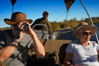 A couple of tourists enjoy a boat safari from Camp Eagle Island Camp by Orient Express , outside the Moremi Game Reserve in Botswana . Moremi Crossing is located in the southernmost part of Chief's Island, a small island full of palm trees and different trees , called Ntswi . This island is surrounded by the rich alluvial plains of Moremi . Access is by plane , after a short scenic flight from Maun for about 20 minutes. During this fascinating scenic flight over the Okavango Delta , enjoy the exciting drawings created meandering waterways and contrasting colors with land areas that rise above the waters of the Delta . In the north of the Okavango Delta waters flowing quickly and the view is limited by the high reeds and papyrus growing on the edge of the channels. In the area south of the Delta, around MOREMI CROSSING, enjoying sweeping views of the floodplains of the Moremi Reserve