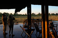A couple of tourists on the porch outside the camp Khwai River Lodge by Orient Express in Botswana , within the Moremi Game Reserve Wild . Khwai River Lodge is situated on the banks of the Khwai River , adjacent to the Moremi Game Reserve and the Okavango Delta outside . Khwai River Lodge is one of the oldest hotel- safari Botswana , opened in the late 60s by the late Sir Seretse Khama , the first president of independent Botswana . It is situated on ancient indigenous plants and fig trees , eight kilometers northwest of the north gate of the Moremi Wildlife Reserve hunting . Moreover, with its views overlooking the Khwai River and is the perfect place to watch the scenery of the African savannah perennial and discover its varied species of birds. Khwai River forms part of the Okavango Delta . The camp is located in Moremi , one of the largest reserves in Africa majesty house boasts the largest specimens , fast , bright and beautiful , as the abundant crocodiles and hippopotamuses that dwell in the land or herds of zebras and antelopes satisfied tear the grass surface . Where they are fed all kinds of predators lurking lions, leopards and panthers , hyenas and wild dogs.