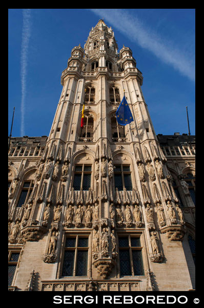 Hôtel de Ville. The town hall, which occupies the southwest facade is the only medieval building left standing today and was built between 1402 and 1455 probably by Jean Bornoy. Its tower, asymmetrical with respect to the building, 96 feet high, is of Gothic style and was designed by Jean van Ruysbroeck in 1449. An urban legend that the architect, to verify the alleged error that the tower will be located in the center, got into it and he jumped, although in truth both parties were not built at the same time. Atop the tower is a high bronze statue of five meters of the archangel Michael, patron saint of Brussels, slaying a dragon or devil. The left part of the council consists of twelve arches, including the bell tower, representing the twelve stages wet alchemy. Instead, the right side only has seven arches, counting the bell, symbolizing the new alchemy dry in seven stages. The facade is decorated with numerous statues representing nobles, saints, and allegorical figures. Contrapicado THE GRAND PLACE BRUSSELS TOWN HALL