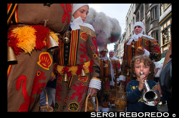 The Belgian festival Binche with their traditional costumes: Eastern princes, sailors and harlequins through the streets of Brussels. An amazing procession through the cobbled streets of the city to the beat of drums and artists with their wax masks and ostrich feathers. Quite an experience. CHILD PLAYING DRESS TRUMPET BINCHE.