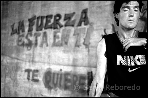 CAN TUNIS BARCELONA DRUGS Francisco Morales Diaz casi entrando en sobredosis con una camiseta NIKE. En la pared reza: La fuerza está en ti. Antes, eso sí, me habían proyectado un vídeo, y me habían dado unas cuantas recomendaciones para mi seguridad personal. No lo sabía pero a aquello se le llama un “briefing”, una reunión informativa. Estaba convencido de que me darían  un té con pastas, o un cocktail de bienvenida, como en los cruceros de lujo, tipo “Vacaciones en el Mar”,  pero no fue así. Eran unos cuantos consejos pronunciados con tono imperativo, con la voz que emplean las azafatas de los aviones, cuando muestran a los pasajeros el uso de los chalecos salvavidas, a base de “en caso de que se enciendan las señales luminosas,  apaguen los cigarrillos, tiren fuertemente de la mascarilla....”. Habían serías dudas, sobre la conveniencia de mi calzado, y como aquel que no quiere la cosa, recordaban casos en que transeúntes ocasionales se habían pinchado con jeringuillas ya utilizadas, y susceptibles, por tanto, de estar infectadas. Además me explicaron que íbamos provistos de una sirena, por si la cosa se ponía fea, y en caso de que la señal se pusiera en funcionamiento había que salir de allá zumbando. El nivel previo de acojonamiento era indescriptible, el miedo atroz.  