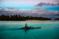 Aitutaki. Cook Island. Polynesia. South Pacific Ocean. A tourist practiced rowing next to the beachside Aitutaki Lagoon Resort & Spa Hotel. Aitutaki Lagoon Resort’s staff are here to help with all your questions and activity needs. From our reception desk hire motor scooters, bicycles or a car to tour the island or book an organised tour – scuba diving, deep sea fishing, lagoon cruises and much more. Two dedicated activities staff are available to help you enjoy our complimentary canoes, kayaks, windsurfers, snorkelling equipment, beach volleyball, reef walks and more. The famous Aitutaki Lagoon Cruise departs from the resort entrance. Simply book your ticket at reception and prepare for an amazing day of turquoise water, deserted islands and fresh fish BBQ.  Restaurants & Entertainment: Our two restaurants provide excellent dining and entertainment. Indulge in a cocktail before dinner at Are Kai Kai Restaurant or try lunch at beach side Ru's Bar & Grill. Every night brings superb Polynesian entertainment including a traditional dance and drum show right on the beach. Join us under the stars.. Aitutaki Lagoon Resort & Spa is the Cook Islands’ only private island resort, and the only resort on the world’s most beautiful lagoon, fabled Aitutaki Lagoon. This intimate resort offers the Cook Islands’ only Overwater Bungalows and now, new Premium Beachfront Bungalows. 