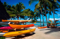 Aitutaki. Cook Island. Polynesia. South Pacific Ocean. Some kayaks await tourists on the beach in Aitutaki Lagoon Resort & Spa Hotel.  Go Kayaking - Kayaking is an easy, fun, and relaxed way to explore the lagoon around Rarotonga island. The best place for kayaking on Rarotonga is around Muri Beach and the southeast coast near four uninhabited islands. The Cook Islands consist of 15 islands scattered over an area of about 2 million square kilometers in the Pacific Ocean. The islands are little snippets of paradise that invite you to come and get away from it all, to soak in the sun and thousands of years of Polynesian history and culture. Rarotonga is the largest and most visited island. This place is completely surrounded by a reef which means beautiful white beaches and tropical turquoise waters, while imposing mountain peaks, interspersed with dense rain forest, make for some fantastic scenery on the island.   Muri Beach - This popular beach is situated on the southeast corner of Rarotonga and is protected by a lagoon. A kayak or canoe can be hired here for about $13 USD for a day. There is good snorkeling too. Aitutaki Day Cruise - The southern island of Aitutaki boasts the world’s largest coral lagoons, inhabited by huge clams and multicolored tropical fish. Scuba Diving - The dive sites on the Cook Islands are considered perfect for beginner divers because the sites are close to the shore and the currents aren’t too strong. Te Vara Nui Village - Te Vara Nui Village is the cultural center where you can learn about the history of the native population. Ura Po is a popular thing to do. It is a dining and island night show on floating and fixed stages set in botanical gardens surrounded by waterfalls. 