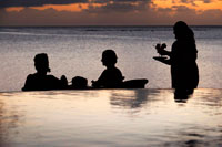 Aitutaki. Cook Island. Polynesia. South Pacific Ocean. A waitress serves delicious cocktails by the beach at the luxurious Hotel Pacific Resort Aitutaki. Pacific Resort Aitutaki is an intimate collection of 27 absolute beachfront bungalows, suites and villas all with their own unique view of the world famous Aitutaki Lagoon. This Cook Islands accommodation features memorable sunsets and a tranquil island setting for the most relaxing of holidays. There is no better place to spend your Cook Islands honeymoon. 2012 was a busy year for PRHG boasting numerous international travel award accolades that clearly consolidate its position as the best in its class across the across the South Pacific and along the way putting the Cook Islands on the map in terms of excellence in quality, service, hospitality and guest experience. Awards picked up last year include HM Awards for Hotel & Accommodation Excellence, World Travel Awards, TripAdvisor Awards & New Zealand Travel Industry Awards. 2013 is looking to follow suit. And when it’s time to shop for a souvenir or a gift to take home from your Aitutaki travel, then you can find shops in Aitutaki with hand painted pareaus and tropical shirts to remind you of your Aitutaki lagoon vacation. You may even come across a coconut bra or a ukulele while shopping in Aitutaki Cook Islands, so you can show the folks back home what an Island Night is like!. 