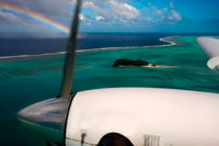 Aitutaki. Cook Island. Polynesia. South Pacific Ocean. A plane flies over the islands between the Aitutaki Island and Atiu Island with a rainbow background. THE first man who came to Aitutaki from Avaiki [Hawaiki] was Ru. He came in a canoe named Nga-Puariki, seeking for new lands. The canoe was a large double one, a katea, namely two canoes fastened together. The name of the cross-pieces of wood which fasten on the outriggers are called kiato. The names of the kiato were as follows: the foremost Tane-mai-tai, the centre one Te-pou-o-Tangaroa, and the after one Rima-auru. They arrived at the island and entered a passage named Aumoana. They landed and erected a Ma, which they named Pauriki, after their canoe. (Ma means a place of evil spirits.) They also erected a Ma inland, which they named Vaikuriri, which was the name of Ru’s god, Kuriri, brought with them from Avaiki. Ru called the land Araura, which means, the place to which the wind drove him in his search for land. He appointed a number of Koromatua as lords of the island, (Koromatua=literally, old people, or tupuna.) Their names were: E Rongo-turu-kiau, E Rongo-te-Pureiau, Mata-ngaae-kotingarua, Tai-teke-te-ivi-o-te-rangi, Iva-ii-marae-ara, Ukui-e-Veri, Taakoi-i-tetaora. These were the lords of the island as appointed by Ru. There remained the rest of the people who came with him, consisting of men, women and children. Ru’s people must have numbered over 200. These people settled down on the land and increased to a large number. It was said that it was Ru who raised the heavens, as they were resting before his time on the broad leaves of plants, called rau-teve. 