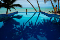 Rarotonga Island. Cook Island. Polynesia. South Pacific Ocean. Pool of luxury hotel Little Polynesian Resort in Rarotonga. The Little Polynesian is a boutique resort on the southern side of Rarotonga. It consists mostly of beachside bungalows and a couple of smaller garden bungalows. Whilst some of the other resorts situated at nearby Muri have better access to the lagoon and small islands, the Little Polynesian's beach location is pretty and convenient for swimming and other waterspouts. Little Polynesian Resort is on the edge of Rarotonga`s marine haven, Titikaveka Lagoon whose white sandy beaches and crystal blue water are the ultimate tropical holiday delight. For luxury Cook Islands accommodation that inspires romance and intimacy like no other, Little Polynesian Resort is a must see destination. This boutique island resort is perfect for your romantic getaway or honeymoon. The outstanding and personalised service will ensure you feel like the only guests in the resort. Relaxation is assured as you look out over the tropical turquoise waters and are surrounded by lush tropical gardens. With a restaurant and bar on site, snorkelling and kayak equipment available and the stunning beauty of the natural environment guests will have all their needs taken care of. The staff at Little Polynesian Resort are also happy to help book local tours and sightseeing to assist guests in getting out to explore the island if they so desire. Little Polynesian Resort consists of 10 Over Beach Ares and 4 Garden Ares. 