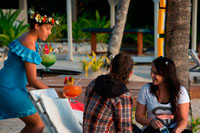 Rarotonga Island. Cook Island. Polynesia. South Pacific Ocean. A tourist couple enjoying huge cocktails by the beach in the Hotel Crown Beach Resort & Spa.  Crown Beach Resort & Spa presents a private secluded space for just 36 couples to escape in 5 acres of tropical gardens and an endless icing sugar beach that caresses a sparkling blue lagoon. Ridiculously romantic, Crown Beach Resort & Spa is located on the sheltered sunset coast of Rarotonga where 5 acres of botanical gardens and an endless icing sugar beach caresses a sparkling blue lagoon. Crown Beach Resort & Spa offers a private and secluded haven for just 42 couples to frolic in uninterrupted space and unhurried time. Our villas and suites present king bedrooms adorned with lavish textures in neutral tones that warm the soul - choose from your own private swimming pool or Jacuzzi. This place is sure to unleash your desire with the one you love. Crown Beach Resort & Spa is your key for pure bliss and luxurious romantic salvation.