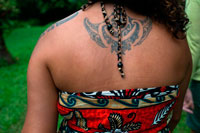 Rarotonga Island. Cook Island. Polynesia. South Pacific Ocean. A woman showing her back in a typical Polynesian or maorí tattoo. The Polynesian tattoo symbols of spear heads can be found in almost every Polynesian tattoo design. It’s designed to express courage and fight. It’s also used to represent warrior, sharp items, and sting of animals and rays. Spear heads are usually used in combination with other symbols to express certain meanings. For example, one line of spear heads and one line of enatas upside down along its side can express the meaning of defeating enemies. T? moko is the permanent body and face marking by M?ori, the indigenous people of New Zealand. Traditionally it is distinct from tattoo and tatau in that the skin was carved by uhi  (chisels) rather than punctured. This left the skin with grooves, rather than a smooth surface. Tattoo arts are common in the Eastern Polynesian homeland of M?ori, and the traditional implements and methods employed were similar to those used in other parts of Polynesia (see Buck 1974:296, cited in References below). In pre-European M?ori culture, many if not most high-ranking persons received moko, and those who went without them were seen as persons of lower social status. Receiving moko constituted an important milestone between childhood and adulthood, and was accompanied by many rites and rituals. 