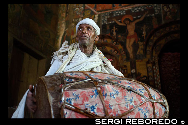 A priest makes drumming inside Debre Birhan Selassie Church (also called the Cherubim. Just outside the town of Gondar is the Debre Birhan Selassie church known for its murals, located on a hill above the city, with beautifully painted walls that have many religious stories. If you look up the eighty heads are winged Ethiopian cherubs smiling, each with a slightly different expression.'s most famous ceiling Ethiopia.
