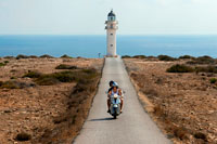 Formentera. Two young motorcyclists on a long road to Es Cap de Barbaria lighthouse, in Formentera, Balears Islands. Spain. Barbaria cape formentera lighthouse road.