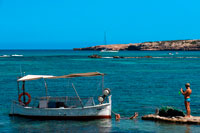 Formentera. Els Pujols beach in Formentera. Tourists taken pictures with traditional fishing boat in summer day. Llaüt. 
