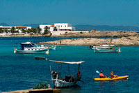 Formentera. Els Pujols beach in Formentera with traditional fishing boat and kayaks in summer day. Llaüt boats.