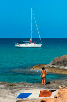 Formentera. Nude woman in Es Calo beach, Formentera Island, Mediterranean sea, Balearic Islands, Spain. Es Calo de San Agusti with boat in Formentera island turquoise mediterranean. 