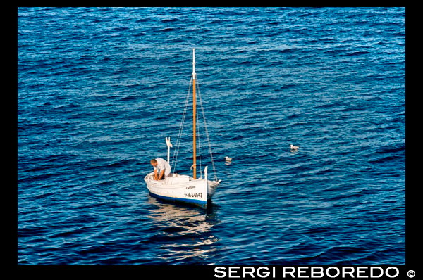Fisher with traditional fishing boat in summer day. Llaüt.  Mercifully, and despite the appalling weather conditions that day, signal reception held-up and the patron saint of Catalan fishermen responded to the prayer with a message to remove the sinking boat’s rudder. Our stalwart mariner, by now up to his plums in freezing briny, just managed to complete this task before his stricken vessel disappeared beneath the surface. Miraculously the howling wind turned around and clinging to the wooden rudder for buoyancy Josep was blown back towards the harbour where eager hands dragged him safely ashore. A poor fisherman with no insurance, Josep could ill-afford the cost of building a new boat with which to continue his livelihood. On the bright side however, at least he didn’t have to buy a new rudder.