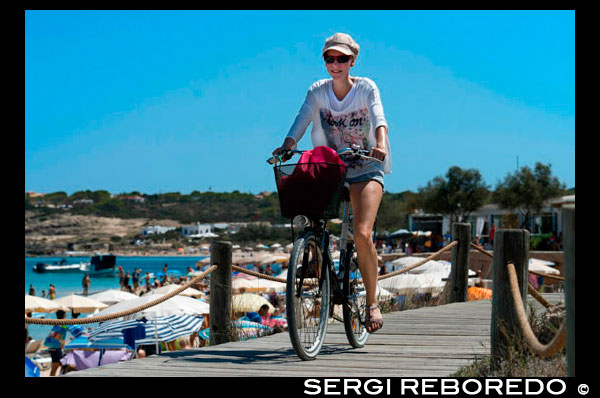 Es Pujols, beach, Formentera. Girl riding bicycle. Panoramic view, parasol, deck chair, tourism, holiday. Spain, Balearic Islands, south of Ibiza island, Formentera island, Es Pujols beach. Spain; Formentera; Es Pujols; beach; pujols; background people; balearic; balearic islands; beach; es pujols beach; girl; woman; bicycle; bike; atractive; tour; eco; ecology; sea; active; europe; formentera island; general view; bath; sun; islands; littoral; mediterranean sea; parasol; people; sea; south; spain; tourism; tourist; vacations; island; balearic; Baleares; background; balearic; beach; beautiful; blue; calm; coast; europe; exotic; formentera; holiday; idyllic; island; islet; landmark; landscape; llevant; mediterranean; nature; ocean; outdoor; paradise; places; reflection; sand; scenic; sea; seascape; shallow; shore; sky; spain; summer; sunlight; sunny; tanga; tourism; touristic; transparent; travel; tropic; tropical; turquoise; vacation; water; waves; wavy; wet; white; atrraction; destination; Europe; European; holiday; travel; islands; mediterranean; photos; place; spanish; sun; tourism; touristic; vacation; view; Balearics; beautiful; beauty; paradise; fun; happy; coastal; paradisiac; popular