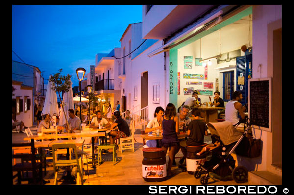 Tourists, Big Store,  Bar and restaurant in Isidor Macabich street of Sant Francesc Xavier, San Francisco Javier, Formentera, Pityuses, Balearic Islands, Spain, Europe.  Next to the Constitution square. Spain; Formentera; island; balearic; Sant Francesc; Xavier; San Francisco; Francisco; Javier; main; sunset; square; central; typical; white; houses; house; bar; bars; rentaurant; restaurants; tourists; nice; town hall; day; daylight; daytime; during; europe; european; exterior; exteriors; formentera; holiday; holidays; island; islands; javier; journey; outdoor; photo; photos; pityuses; place; places; san; sant; shot; shots; small; south; southern; spain; spanish; square; squares; tourism; tourists; town; towns; travel; travelling; travels; trip; trips; vacation; vacations; village; villages; Baleares; atrraction; destination; Europe; European; holiday; travel; islands; mediterranean; photos; place; spanish; sun; tourism; touristic; vacation; view; Balearics; beautiful; beauty; paradise; fun; happy; coastal; paradisiac; popular