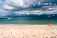 Some tourists walk along the beach to the west of the island, the most uninhabited touristically speaking. Gili Meno.
