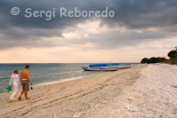 A couple walking along the sandy beach in the west of the island, near the pier Bounty Resort. Gili Meno.
