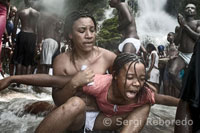 Parishioners and supporters start at an early age. In the photograph a mother holding her daughter while little is in a trance possessed by multiple spirits of voodoo. Women and men of all ages and social classes bathe and pray to purify and cleanse your body. To reach the waterfall the faithful must cross several limestone cliffs. Contact with water represents the climax, but before that happens, the waiting can see how some of his friends move imitating the movement of snakes: they have been possessed by the African goddess Damballah-Wedo. The water falls with great force, so that it is not uncommon to realize that some who are placed under the waterfall allow their clothing to be torn apart, literally.