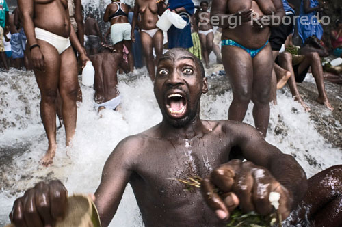 A man in a trance in one of the pools of Saut d'eau. Voodoo Festival Saut d'Eau is celebrated every year on July 16 to coincide with the day on which in 1847 appeared a vision of the Virgin Mary. Thousands of devotees coming from all parts of Haiti are bathed in this water for purified or pra lose the Grand Master that their dreams become reality. Voodoo is the main religion of Haiti. The followers need to be possessed by a spirit Iwa to communicate with Grand Met, since this is abut far from the physical plane. In the photograph, an adept is possessed by the great Iwa. Cries and movements are convulsive. The trance, at which time Iwa spirits enter the body of the followers. From early morning, the faithful Haitians begin to go to cemeteries laden with coffee, "klerec (native of strong drink alcohol) and all types of food to offer to the spirits. Voodoo, although not a form always visible, is present in all areas of the country's life and even the blue and red colors of the flag represent Ogou, spirit of war, fire, and the cosmos. Before the ritual demands that these women consecrated to the voodoo religion purify their bodies and cleanse their sexual organs and the fluid removed from a bottle filled with herbs before receiving the spirit. Violent movements, dancing and alcohol consumption continues to characterize the times that voodoo priestesses lend their bodies to spirits of the dead. The crowd, which always remains about the priests, alive with singing and shouting to them in their contacts with the other world. Another essential feature of this religion of African origin is its deep fluency, partly because it has no liturgy or theology and partly written by the diverse influences that have had other religions.