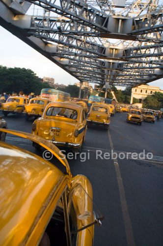 INDIA CRUZANDO EL RIO GANGES El taxi es uno de los iconos de algunos nostálgicos que representan Calcuta. Innumerables giras de amor; muchas visitas turísticas por la ciudad de la alegría ha sido en estos taxis. Después de sobrevivir a muchas rondas de cambio de imagen, como los tranvías y los rickshaws; amenaza toque de campana de los taxis también. Unos 35; 000 taxis capas en estas calles todos los días, transportando al menos tres pasajeros lakh. Sin embargo, los propietarios dicen que su negocio está en su punto más bajo. Gracias a la supuesta avalancha de vehículos de transporte privado y motocarros. "Antes hay ejemplos donde los dueños de ampliar su flota de un solo taxi a 20 taxis. Hoy en día es todo lo contrario. Los dueños de 20 taxis están apenas llegando a mantener dos, "dijo SK Guha, Presidente de la Asociación de Taxistas de Bengala en Calcuta servicio de taxi se inició hace cien años que han sido inmortalizados en muchas películas de directores como Satyajit Ray y Aparna Sen.. . largo de los años taxis evolucionado a través de modelos diferentes para descansar por fin con el Embajador de viejos tiempos. Pero ahora, al igual que la Amby, estos taxis amarillos están perdiendo rápidamente a nuevos chicos de la cuadra ".