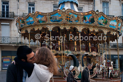 A couple kiss near a wheel located at one end of the Place de la Comedie. Around the Place de la Comedie, the heart of the city with numerous terraces and cafes, you can see performances by musicians and artists, festivals also contribute to its lively cultural and artistic life. Other advantages of this city are its Mediterranean climate, its proximity and good communications with Spain and its proximity to the Pyrenees and the famous Camargue region, with its long sandy beaches and lakes with flamingos wild colonies, ideal for people who love nature and outdoor excursions.