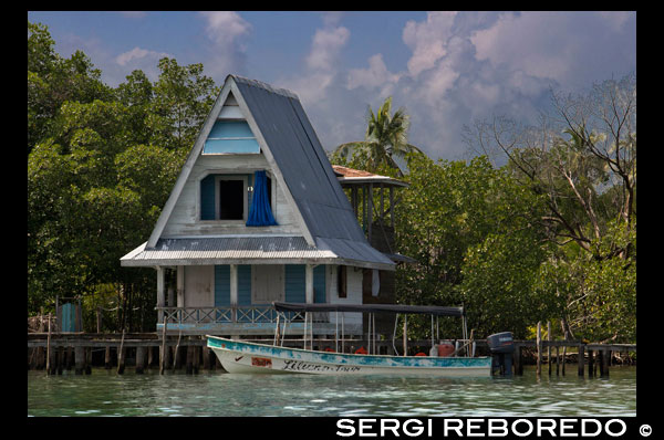 House on stilts over water with solar panels and dense tropical vegetation in background, Bocas del Toro, Caribbean sea, Panama. Tropical cabin over the Caribbean sea in the archipelago of Bocas del Toro, Panama. This is the ideal moment to visit these islands, to time travel and get lost in one of the hundreds of wonderful places that you can enjoy. It is a unique place to find yourself; its lush tropical vegetation, fauna only found in this part of the world, opportunities for diving and snorkeling the unbeatable Caribbean ocean, the possibilities and opportunities for an amazing experience are unbound. With an indescribable and overwhelming natural beauty, added to the great combination of races and ethnicities, living in harmony with indigenous, Western Caribe peoples, Latino’s and extraneros, Bocas del Toro is not just a beautiful archipelago lost in time, blessed by nature -- Bocas del Toro is an example of coexistence and multi-cultural respect for everyone. Welcome to Bocas del Toro archipelago …..you will be amused and amazed, tempted beyond belief and for certain you will to take with you priceless memories of a different world. Enjoy your life….. Enjoy Bocas del Toro! Welcome to an unforgettable vacation.
