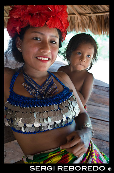 Portrait of native woman and child embera in the village of the Native Indian Embera Tribe, Embera Village, Panama. Panama Embera people Indian Village Indigenous Indio indios natives Native americans locals local Parque National Chagres. Embera Drua. Embera Drua is located on the Upper Chagres River. A dam built on the river in 1924 produced Lake Alajuela, the main water supply to the Panama Canal. The village is four miles upriver from the lake, and encircled by a 129.000 hectare National Park of primary tropical rainforest. Lake Alajuela can be accessed by bus and mini-van from the city of Panama. It lies an hour from the city, close to the town of Las Cumbres. From a spot called Puerto El Corotu (less a port than a muddy bank with a little store that serves as a dock to embark and disembark from canoes) on the shore of the lake, it takes 45 minutes to an hour to climb up the Rio Chagres to Embera Drua ina a motorized dugout. The village was founded in 1975 by Emilio Caisamo and his sons. They first called it community 2.60 as it was the name of the meteorological station constructed by the Panama Canal Commission located a little up river from the present community. The sons married and brought their wives to live in the community which later attracted more families. Most of the villagers moved out from the Darien Region--increasingly dangerous due to incursions by Colombian guerillas and drug traffickers--and to be closer to the city to have better access to its medical services and educational opportunities. In 1996, villagers adopted a name that reflects their identity and began to call their community Embera Drua. In 1998, the village totaled a population of 80. The social and political leadership of the village is divided between the Noko or village chief, the second chief, the secretary, the accountant and all the committees. Each committee has its president, and accountant, and sometimes a secretary. Embera Drua has a tourism committee that organizes itineraries and activities for groups of visitors and an artisans committee to assist artists in selling their intricate baskets and carvings. Such organization is a relatively new phenomenon but it is inspiring to see how the community has embraced it. The village of Embera Drua has its own NGO. Its goals are to support the village and promote tourism and its artisans. Thanks to their efforts, villagers of Embera Drua now own titles to their land. Their main goals are to assist the village in becoming economically self-sufficient. People from the village of Parara Puru lower down Chagres, have joined the NGO as well. If you would like to support their NGO, contact them directly.The climate is tropical with two distinct seasons. The rainy season lasts about seven months from April to October and the dry season is from November to March. The temperature is fairly constant during the year and varies from the high 80's (high 20's C) during mid-day to the 70's (low 20's C) at night. The landscape protects the village from the strong winter winds yet keeps it breezy enough that the village is almost free of biting insects.