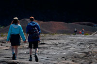 A couple making a trek over the lava of volcano Piton de la Fournaise. Reunion Island is formed by two volcanoes stratum mainly basaltic composition, juxtaposed on the ocean floor and partially emerged: the Piton des Neiges northwest, oldest and extinct 20,000 years ago, culminating at 3070 m. The Piton de la Fournaise is an active volcano that formed on the southeast side of the first and reaches 2631m altitude. The total volume emerged island km3 represents 0.8 x103 to be 1/32 of the total volume of the overall structure. Taking into account the hidden volume in the monoclinal fold of the plate, the part above represents only one hundredth of the total volume. The first eruptive events on the ocean floor at 4000 m depth are estimated occurred 4-5 my ago, the Piton des Neiges has now reached about 7000 m in height from the bottom of the ocean.