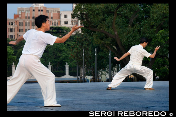Xina, Shanghai, al matí l'exercici de tai-txi al Bund. Shanghi Bund: D'hora tai txi exercicis del matí amb les espases en el Bund a Xangai Xina. Les millors lliçons tai-txi que he tingut eren d'un tipus vell que practicava fora a les 7 am cada matí. Vaig aprendre abril tècniques excel·lents que encara utilitzo en el meu entrenament MMA de manera regular un mètode de captura d'un cop de peu i llençar al teu oponent, la reorientació d'un cop de puny recte i contrarestar en el mateix moviment, la lluita contra el doble underhooks amb un llançament, i escapar d'un pany espatlla mentre la configuració del seu compte. És un art marcial realment fascinant, perquè cada un dels moviments de la dansa com representa una tècnica de lluita pràctica senzilla o estratègia, però és difícil veure com els moviments es tradueixen en aplicacions de combat sense un mestre en l'art demostrar-ho. Però de qualsevol manera, fins i tot sense un mestre de kung-fu, les formes mateixes són un gran exercici de baix impacte que es pot trobar a tota la ciutat de forma gratuïta cada matí. La majoria dels ancians en els parcs no li importarà si etiquetes al llarg, acaba d'aparèixer d'hora i assegureu-vos de preguntar primer si està bé per unir-se a ells. El Bund (que significa el "terraplè") es refereix al famós passeig marítim de Xangai corrent al llarg de la riba oest del riu Huangpu, que forma el límit oriental de l'antiga ciutat de Xangai. Una vegada que un camí de sirga fangosa per vaixells al llarg del riu, el Bund era on les potències estrangeres que van entrar a Xangai després de la Guerra de l'Opi de 1842 van erigir els seus bancs d'estil occidental i diferents cases comercials. Des d'aquí, Xangai es va convertir en líder de la ciutat d'Àsia en els anys 1920 i 1930, un centre comercial i financer cosmopolita i pròspera. Moltes de les estructures colonials impressionants a veure la data d'avui a partir d'aquest moment pròsper i s'han convertit en una part indeleble de paisatge urbà de Xangai. Després de 1949, el carrer va arribar a simbolitzar el domini occidental sobre la Xina i va ser clausurada.