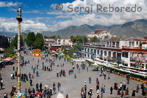 Vistas desde el templo de Jokhang de la plaza Barkhor y el Palacio del Potala al fondo.  Cercana al santuario de Jokhang, la animada plaza Barkhor y las calles colindantes se impregnan del ambiente de la antigua ciudad tibetana de Lhasa. Es una zona llena de contrastes: por una parte, es una de las áreas más sagradas del Tíbet y está inundada de peregrinos, monjes, monjas y templos. Por otra, es el eje del comercio de Lhasa. Los comerciantes de la calle, los vendedores ambulantes y los hombres de negocios se mueven alrededor del área de Barkhor. En la actualidad, esta zona no es simplemente parte de un circuito de peregrinaje, si no también la parte más animada de la ciudad. Aquí se pueden comprar las cosas más curiosas: cuchillos tibetanos, trajes y sombreros tibetanos, tapicerías, instrumentos musicales religiosos, objetos de oro y plata... La oferta de recuerdos mágicos es ilimitada.