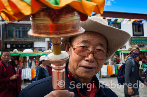 Peregrinos alrededor del templo Jokhang. Lhasa. Cada día miles de tibetanos rezan y cantan plegarias haciendo lo que ellos llaman la kora alrededor del templo Jokhabg . El templo de Jokhang es el principal templo del Budismo Tibetano en Lhasa. Está situado a alrededor de kilómetro y medio del Palacio de Potala inmerso en el barrio con más actividad de la ciudad. Sin duda impresiona recorrer el camino que lleva al Templo. En su entrada principal hay una plaza en la que normalmente se establece un mercadillo en el que se pueden adquirir todo tipo de recuerdos, ropas o arte de la región, de hecho está lleno de tiendas que hacen referencia al arte Tibetano.