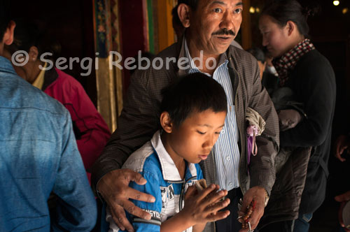 An old man with his son in Tsepak Lhakhang Monastery. Lhasa. Women make a procession around the temple to ask the god of longevity (Cherisi chepal) have a good birth, or elderly people to pray.